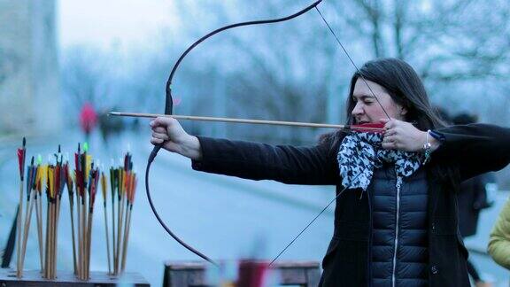 女弓箭手用4K格式的弓射箭女游客一边练习射箭一边对着镜头微笑那个女人专心致志地用箭射中目标