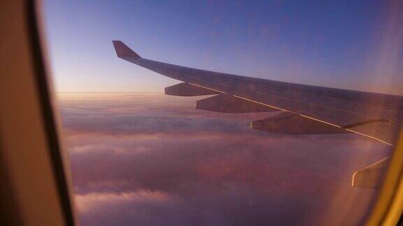 从窗口看飞机的机翼与猩红的日落天空飞过的云