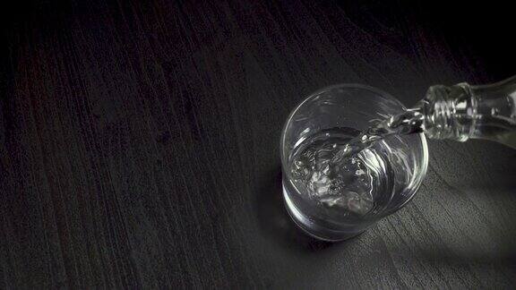 水从一个瓶子倒进一个玻璃杯在桌子上的俯视图慢动作