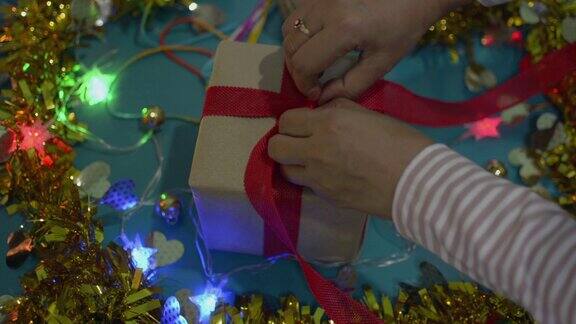 女人的手解开礼物盒上的红色丝带在桌子上为圣诞节和新年