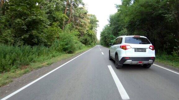 跟随白色汽车穿过森林道路夏日里越野车行驶在美丽的乡间小路上假期去大自然旅行风景优美的景观方式家庭驾车旅行空中