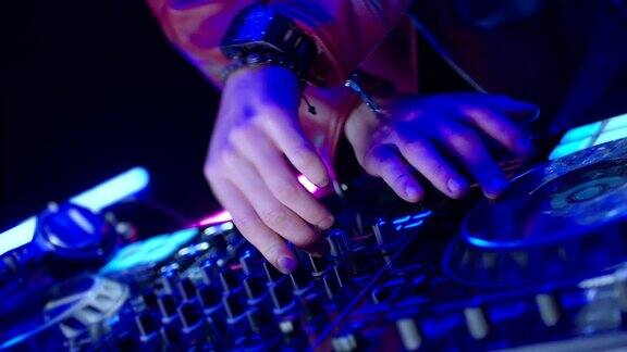 在夜总会迪斯科派对的Dj混合器控制器书桌的特写DJ手触摸按钮和滑块播放电子音乐惊人的近距离DJ手混合和抓挠音乐在乙烯基板