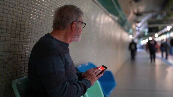 一位老人在等地铁的时候用手机
