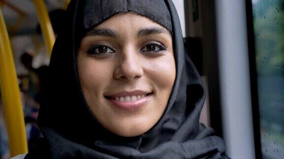 年轻甜美的穆斯林妇女戴着头巾在公交车上看着镜头交通概念城市概念天气概念梦想概念