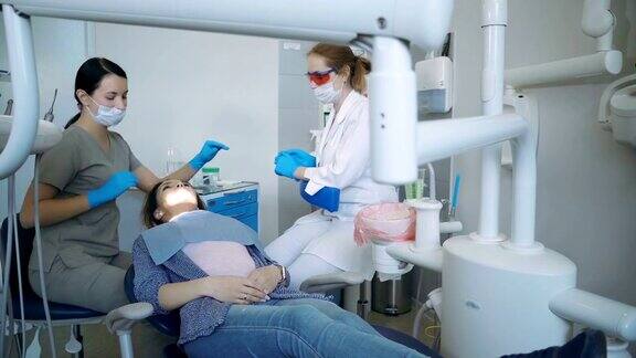 开始牙科治疗医生放下牙科椅牙医打开灯女张开嘴