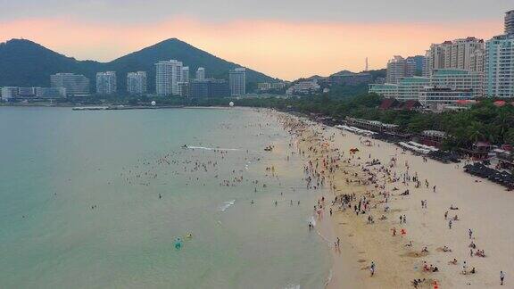日落天空三亚著名的大东海拥挤的海滩航拍全景4k海南中国