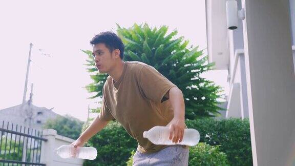 亚洲男人在家用水瓶锻炼