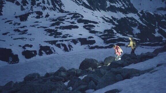 母亲和女儿的登山运动员在黎明攀登雪山脊