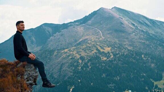 一个快乐的人坐在山的边缘
