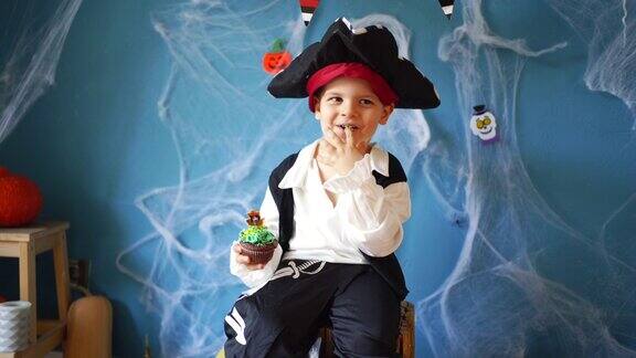 可爱的小男孩穿着海盗万圣节服装在家吃巧克力松饼