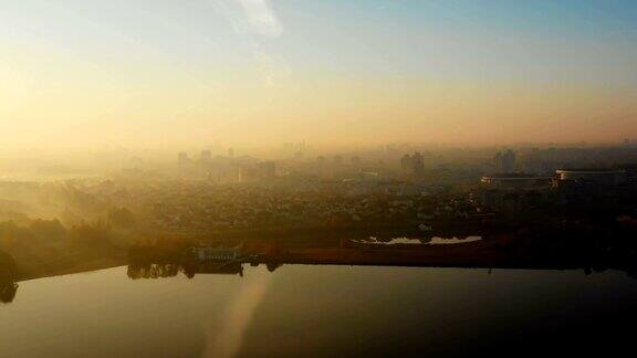 无人驾驶飞机在白俄罗斯明斯克的宏伟城市上升起太阳升起在建筑物和寂静的秋天湖泊上