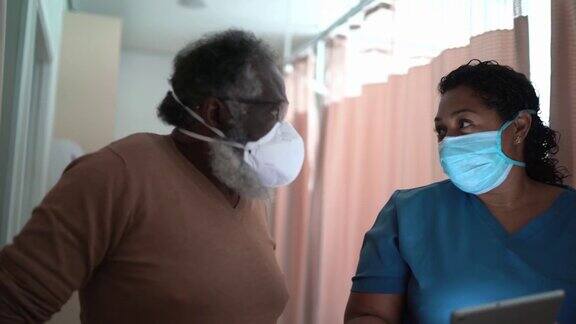 在医院里护士戴着防护口罩与病人交谈