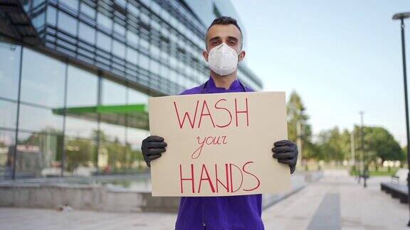流行病学家戴着N95口罩举着写有“洗手”字样的牌子以便在COVID-19大流行期间提高卫生意识