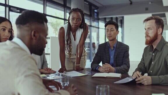 年轻的非洲裔美国商人正在办公室的一张桌子旁开会她正在和同事们交谈商务人士在工作桌上进行会议计划
