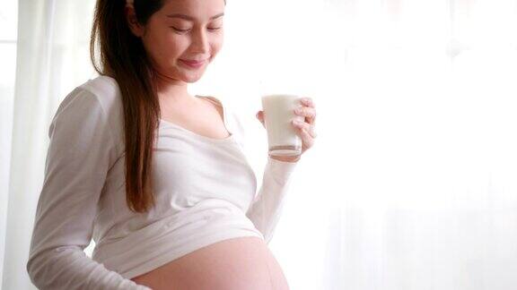 微笑的孕妇喝天然牛奶享受健康饮料、茶点