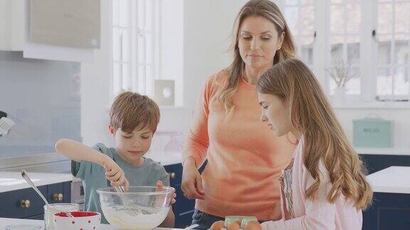 妈妈和两个孩子在厨房里一起做蛋糕
