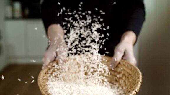 SLOMO女人在柳条碗里筛米