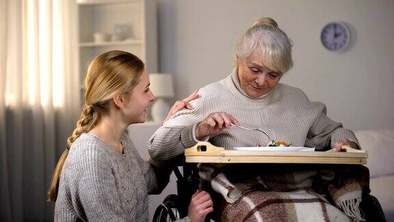 女性志愿者为残疾老妇人提供晚餐老人看护服务