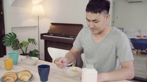 快乐的亚洲人早餐麦片牛奶面包和喝橙汁后早上醒来生活方式男人在家吃食物