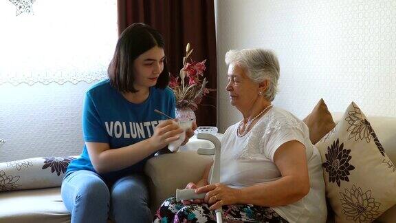 年轻的志愿者在家里给年老的妇女喂食
