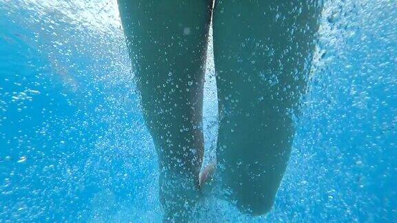 女孩睁着眼睛跳入水中慢镜头中她漂浮在蓝色的泳池边