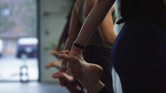 在健身房里一群女人把脚放在身后来伸展她们的四头肌
