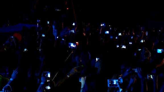 在一场摇滚音乐会中观众拿着智能手机