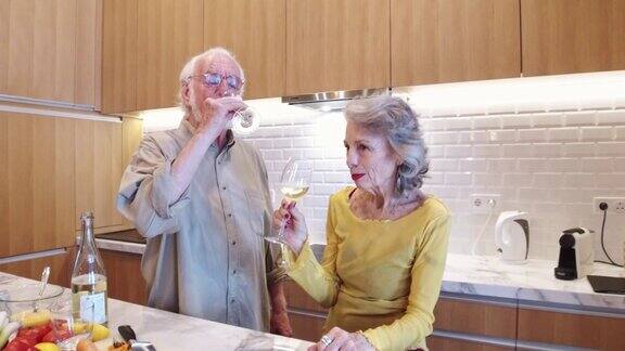 老夫妇在厨房里喝白葡萄酒