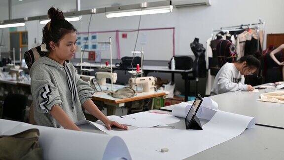 亚洲华裔女时装大学生在学院车间裁剪纸形缝制图案做服装项目