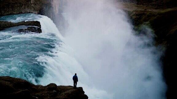 时间流逝的景观在冰岛的海湾瀑布和人站在悬崖边欣赏的观点