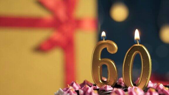 生日蛋糕号60支金色蜡烛用打火机点燃蓝色背景的礼物盒用红丝带系好特写和慢动作