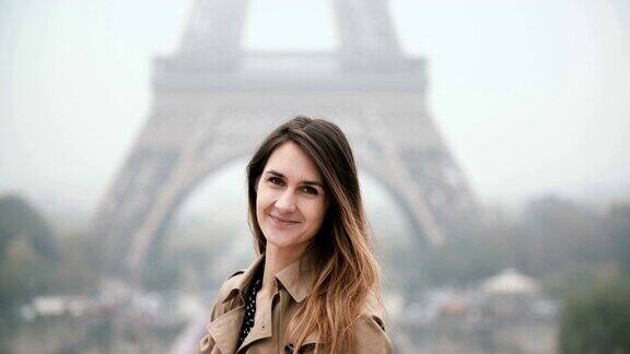 年轻美丽的女子站在法国巴黎埃菲尔铁塔附近转身看着镜头微笑着
