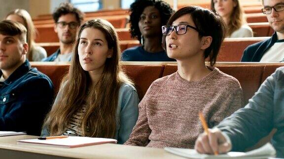 在教室里聪明的亚洲学生问教授一个问题多元种族的现代聪明学生在学院