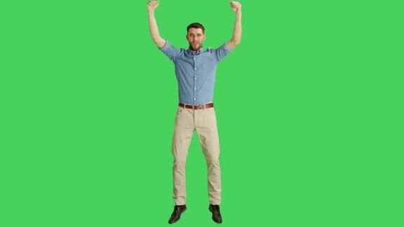 一个快乐随意的男人取得胜利庆祝成功的姿态拍摄在一个绿色屏幕背景