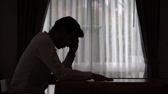 一个悲伤的男人坐在黑暗中的剪影家庭暴力家庭问题压力暴力抑郁和自杀