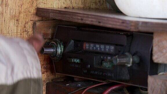 在一艘旧船上一只手在用一台旧收音机换频率