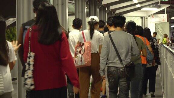 许多人在晚上走在通往阿索克BTS车站的桥上