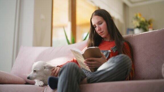 一个女人和她的狗在家里的客厅里读书