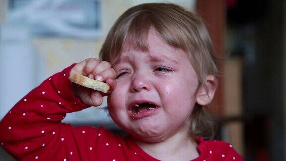 一个哭着的小女孩抱着一块干面包的肖像