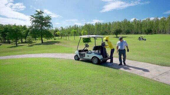 4K亚洲老人在高尔夫球场驾驶高尔夫球车与女球童在果岭打高尔夫球