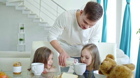 快乐的父亲为女儿们倒牛奶