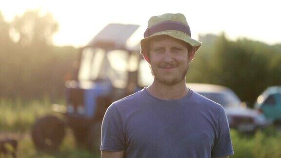 年轻的农民戴着帽子微笑着站在有机农场的田地里
