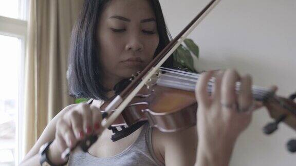 小提琴家在家里拉小提琴的亚洲妇女