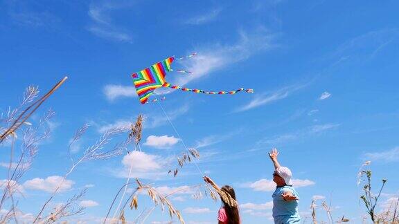 幸福的家庭爸爸和女儿放着五颜六色的风筝站在一个带着小穗的田野里映衬着蓝天阳光明媚的夏天