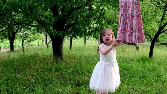 一个可爱的女孩在自然花园里跳舞小女孩在小蹦床上又跳又跳小女孩穿着白色的婚纱