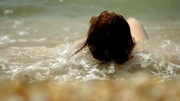 美丽快乐的女人穿着泳衣躺在沙滩上海浪冲击着地中海海岸希腊缓慢的运动高清