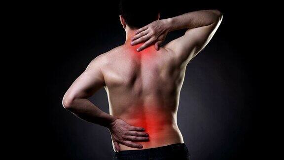 背部疼痛背部疼痛的男人在黑色背景上