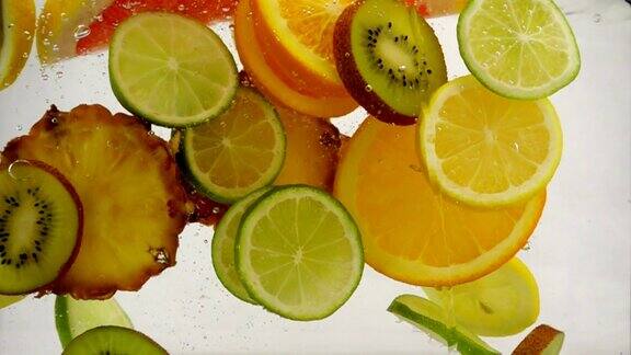 不同的水果片落入水中多汁果汁慢镜头特写