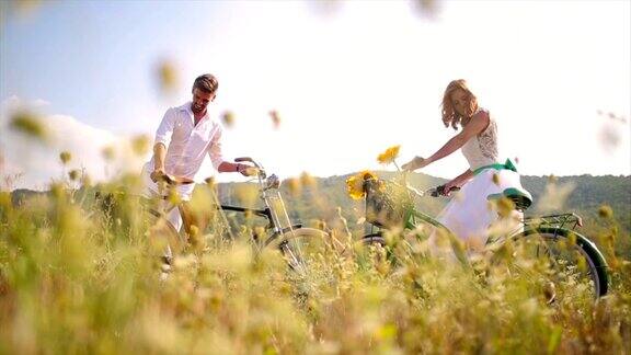 年轻浪漫的夫妇在田野里骑着自行车