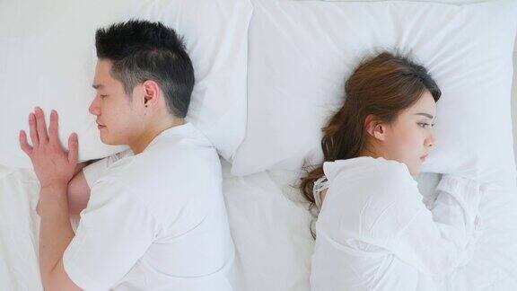 亚洲年轻夫妇躺在床上痛苦的争吵后打架新婚男女因争吵冲突而心碎睡在卧室里家庭problem-separation概念